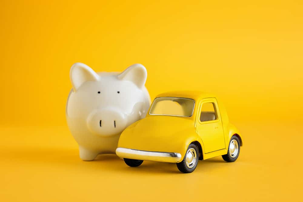 A piggy bank beside a model car